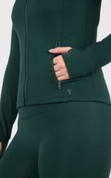 Deep forest-green jacket with front zipper and fitted matching ankle tights, shown as a sleek athletic set.