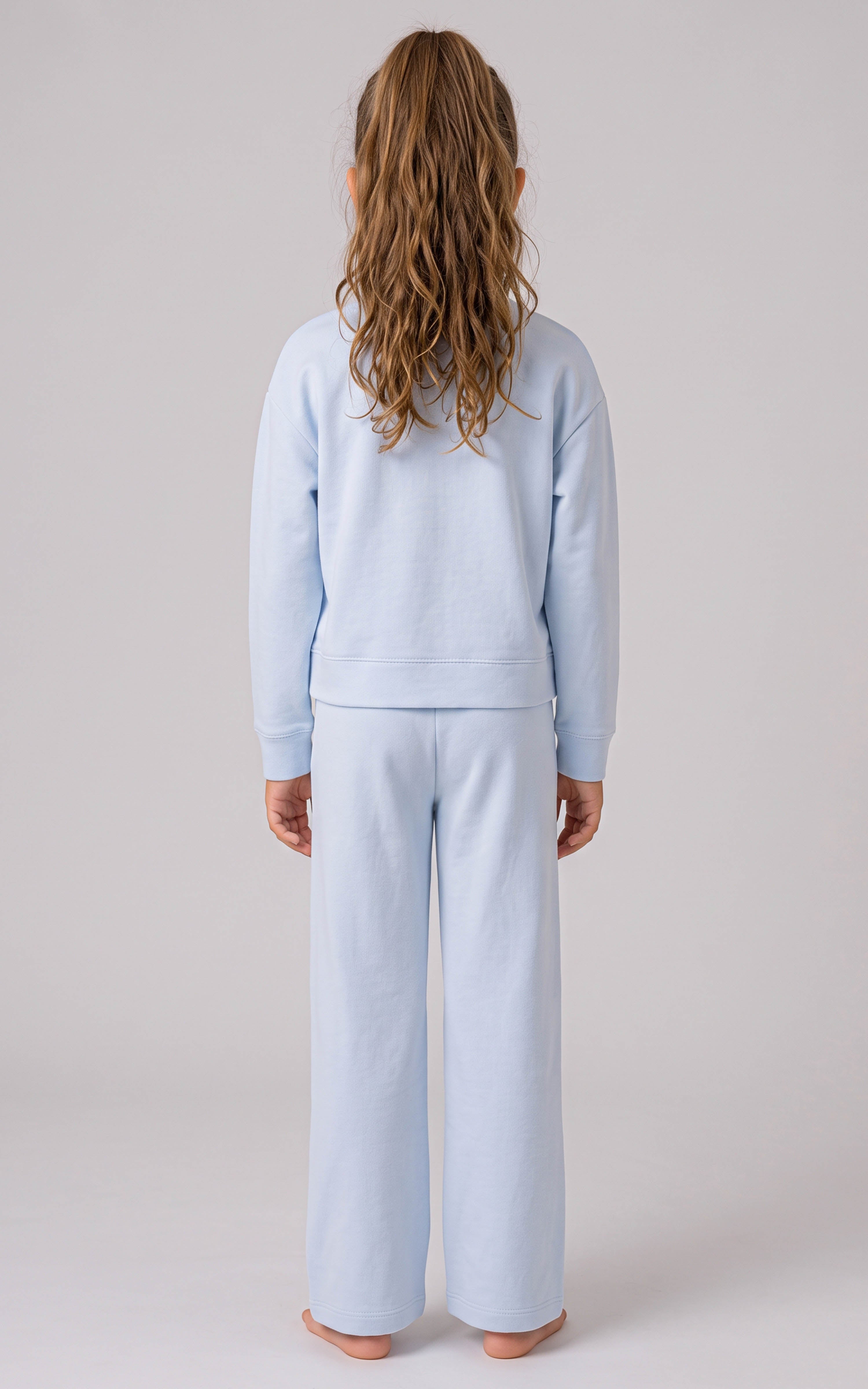 Back view of a girl wearing a pale blue ribbed crewneck top and loose, wide-leg pants with side slits.
