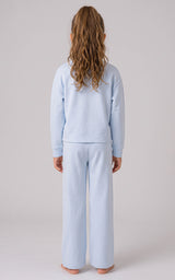 Back view of a girl wearing a pale blue ribbed crewneck top and loose, wide-leg pants with side slits.