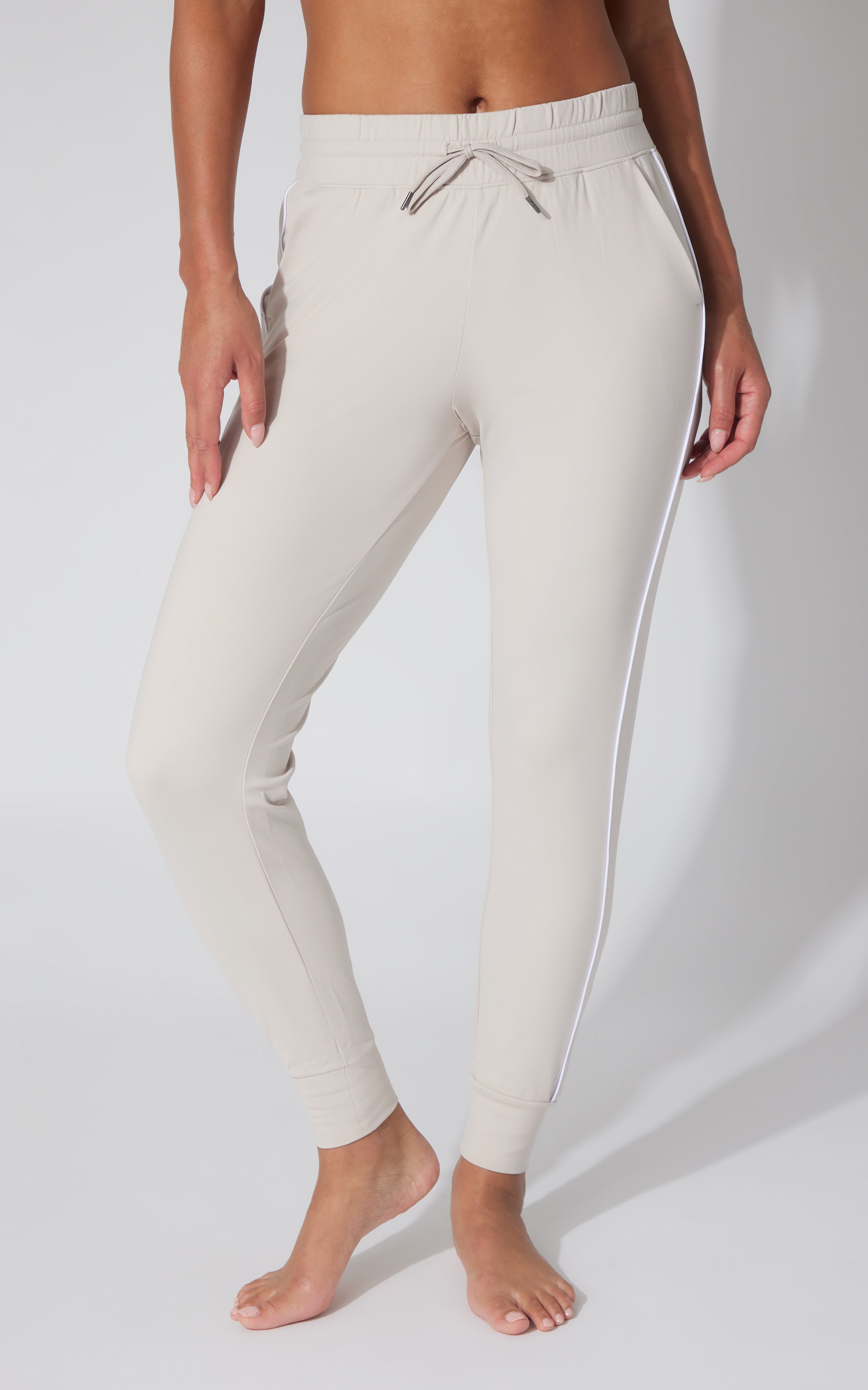 Light beige fleece joggers with drawstring waist and side piping, tapered fit.