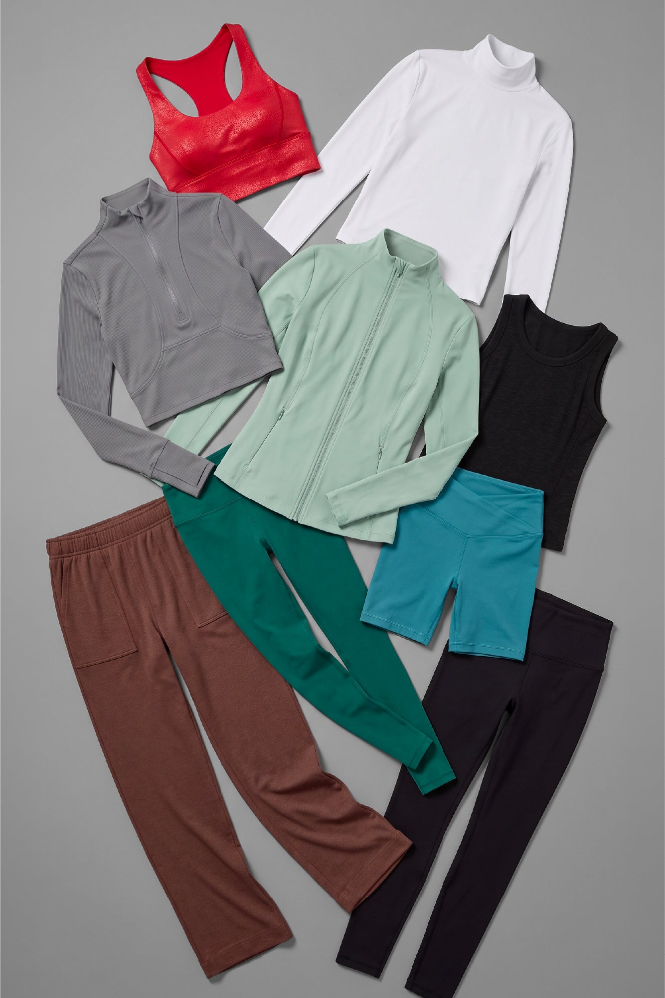 Red sports bra, white long-sleeve top, gray quarter-zip jacket, light green zip-up jacket, black tank top, brown sweatpants, .