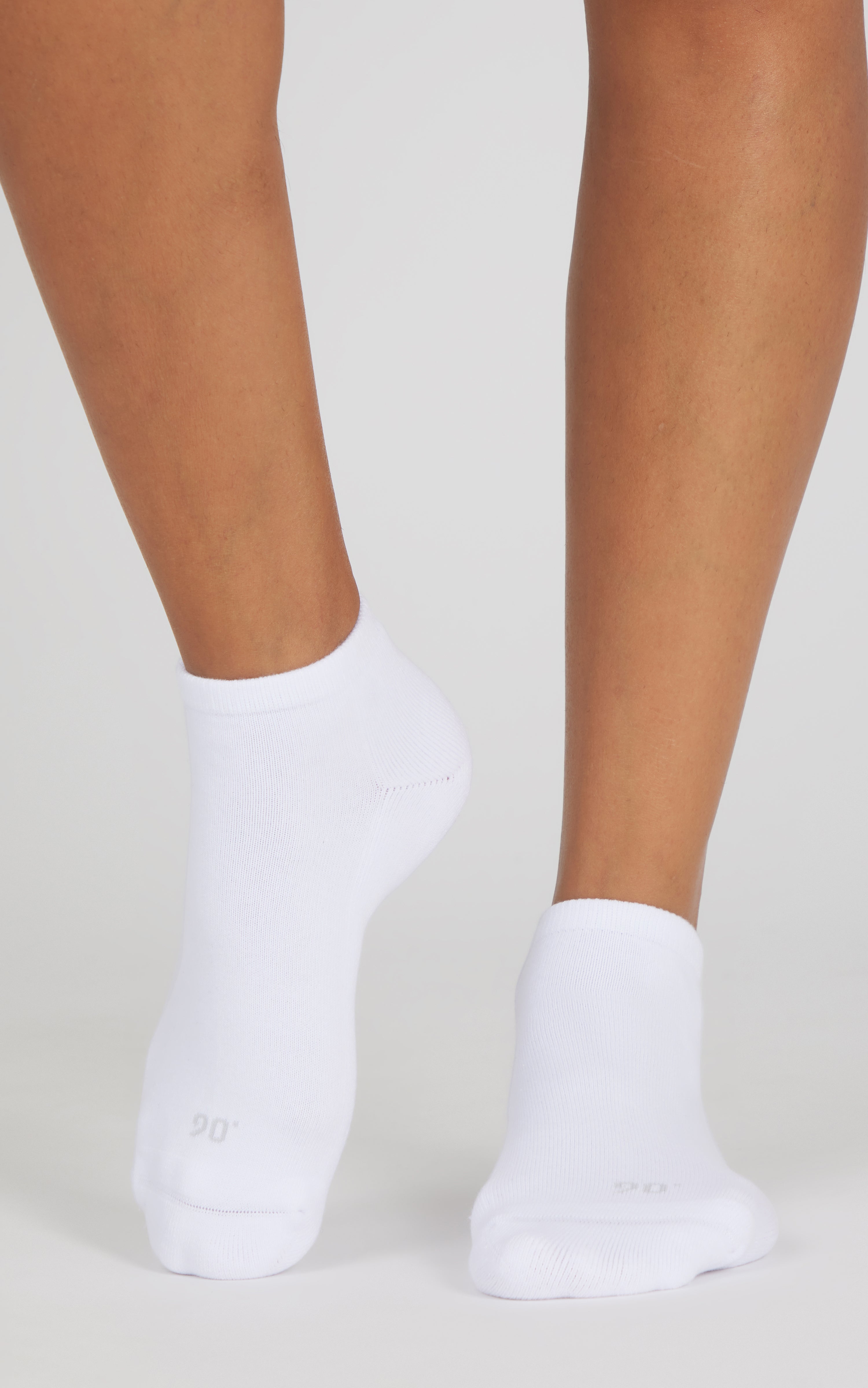 White low-cut socks worn on feet, with a smooth knit texture and ankle-baring fit.