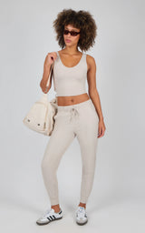 Light beige jogger pants with side pockets, slim fit, and drawstring waist, paired with a white cropped tank and white.