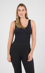 Woman wearing a black cropped tank top with a scoop neckline and wide straps, paired with black leggings.