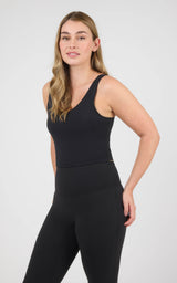 Black cropped tank top with a scoop neck, wide straps, and a built-in bra, paired with black leggings.
