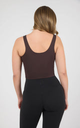 Woman modeling a dark brown cropped tank with a scoop back and wide straps, paired with black leggings.