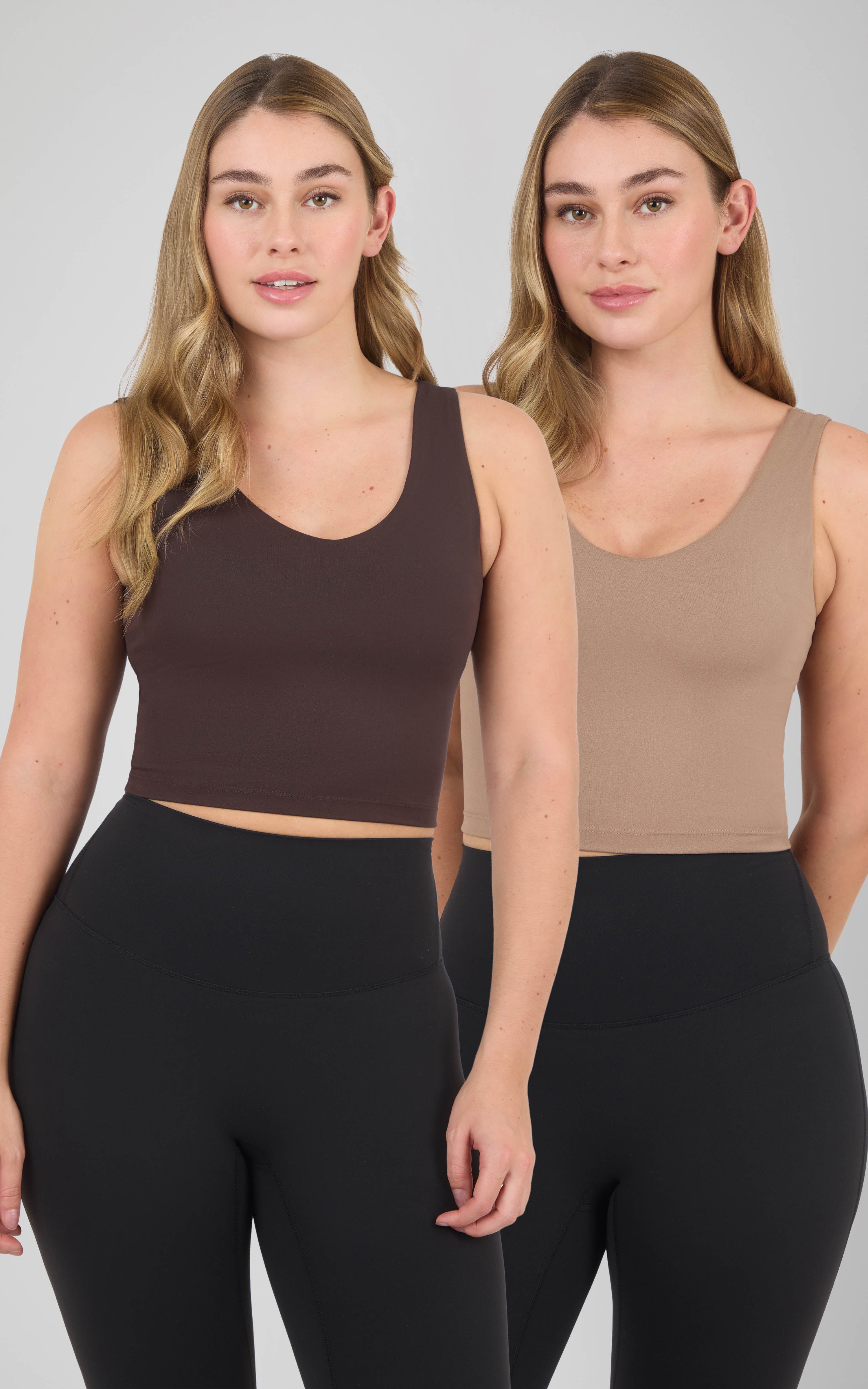 Two women model cropped scoop-neck tank tops with built-in bras in dark brown and beige, paired with black leggings.