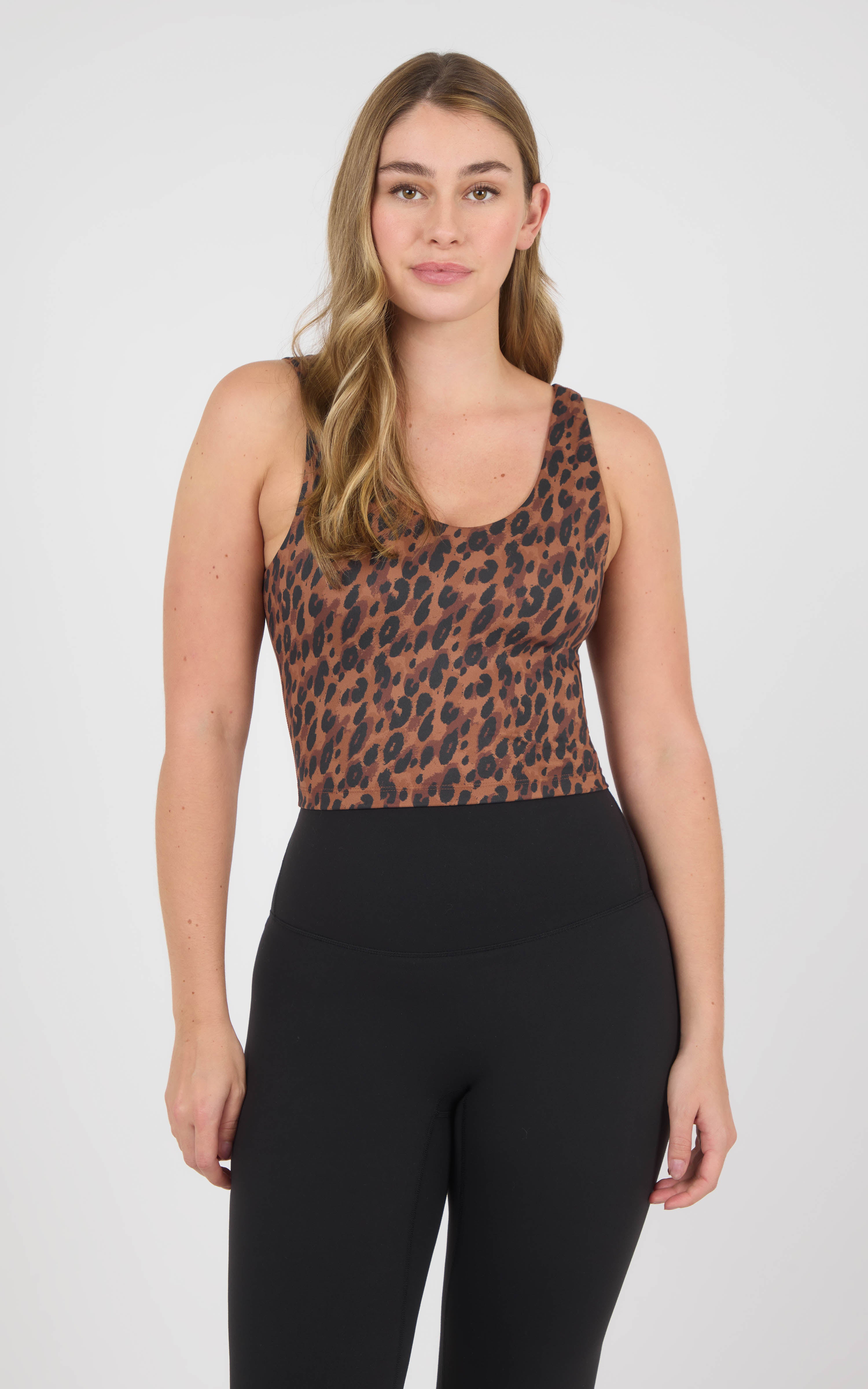 Woman wearing a cropped scoop-neck tank with a built-in bra and brown-and-blue animal print, paired with black leggings.
