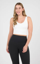Woman wearing a white cropped scoop-neck tank with a built-in bra and black high-waisted leggings.