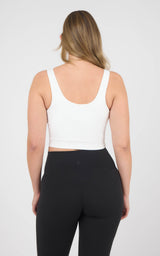 Back view of a white cropped tank with wide straps and a low scoop back, worn with black leggings.