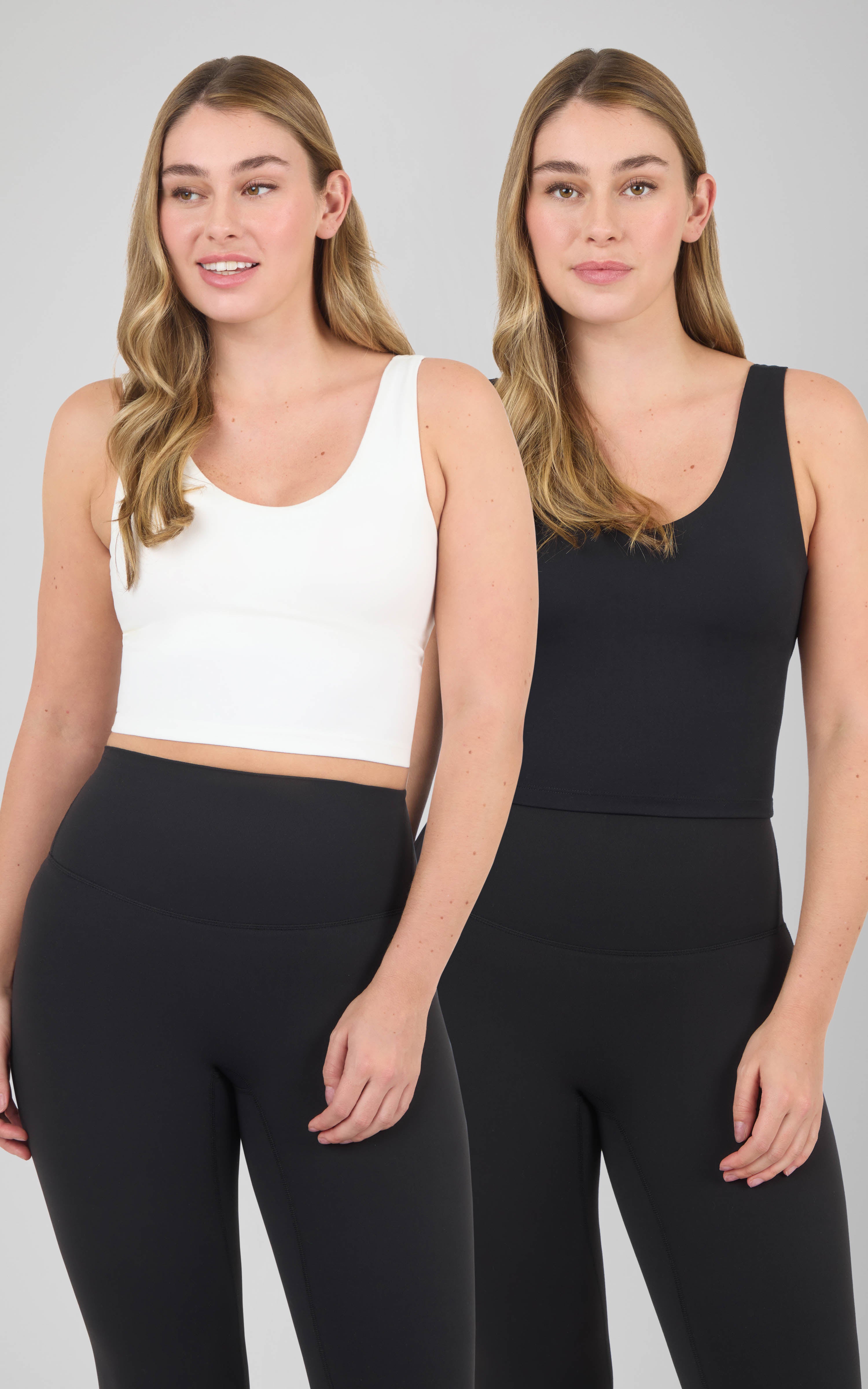 Two cropped scoop-neck tanks with built-in bras, one white and one black, modeled with black leggings.