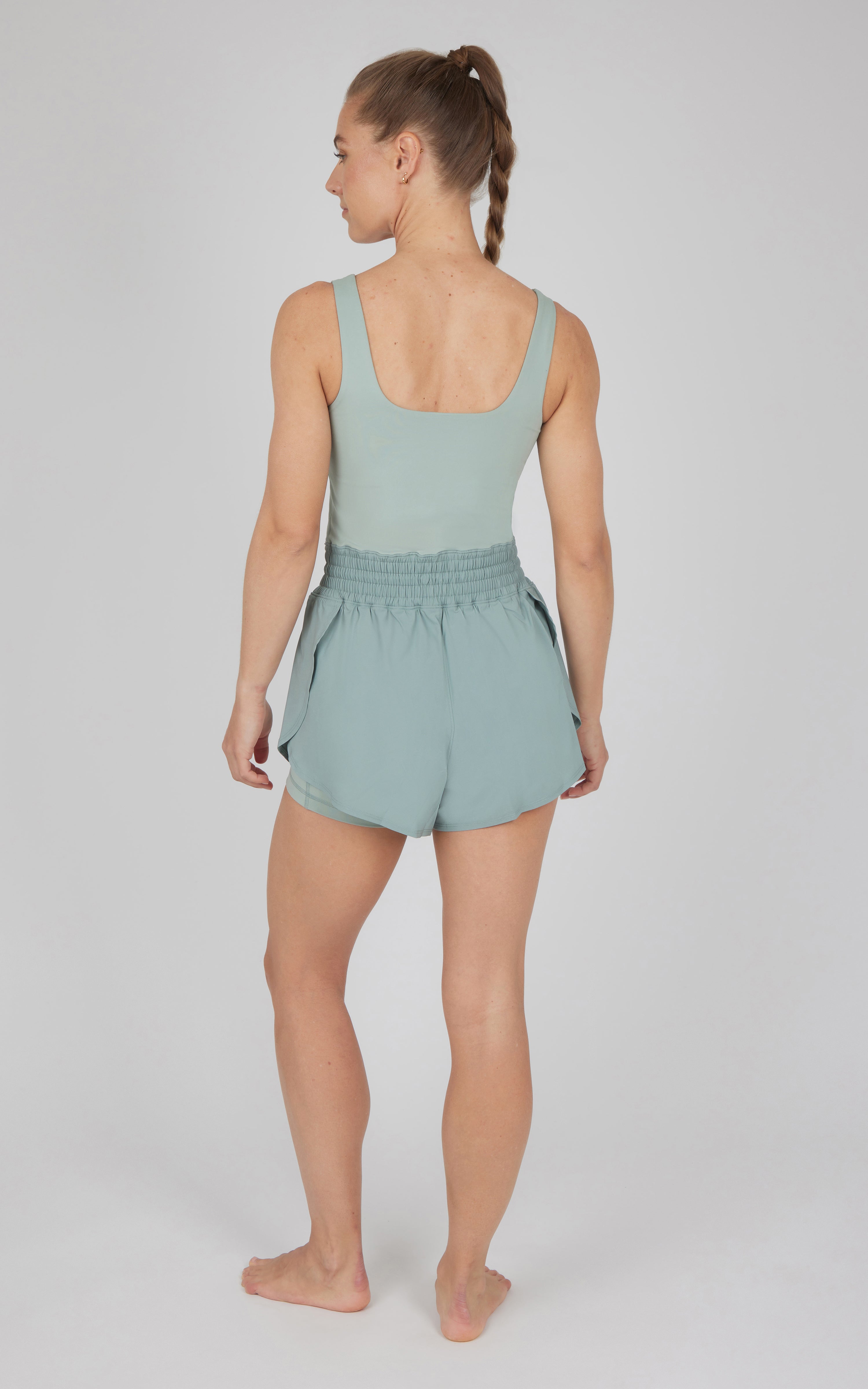 Women's sleeveless green romper with elastic waist and relaxed shorts back view.