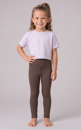 Little girl wearing full-length dark brown leggings with a fitted stretch silhouette and a cropped lavender T-shirt.