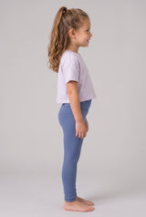Little girl in profile wearing full-length blue leggings and a lavender short-sleeve shirt.