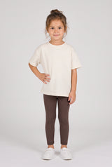 Toddler girl wearing fitted dark brown leggings with a soft matte finish and a white T-shirt.
