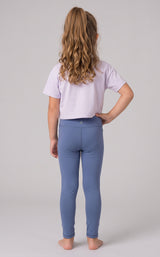 Little girl modeling full-length slate blue leggings with a fitted, stretchy look, shown from behind.