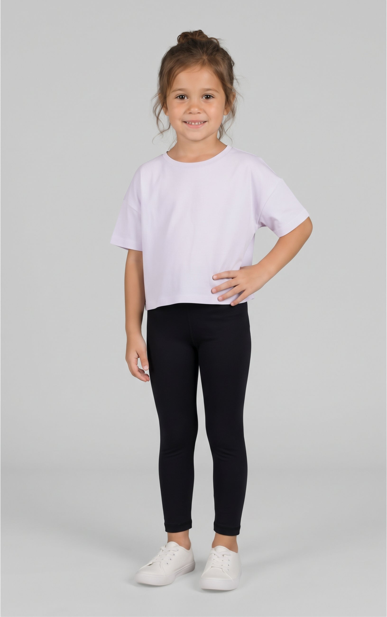 Toddler girl wearing black full-length leggings with a soft, slim fit, paired with a white T-shirt and sneakers.