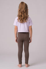 Back view of a girl wearing full-length dark taupe leggings with a soft, fitted stretch fabric and a lavender cropped.