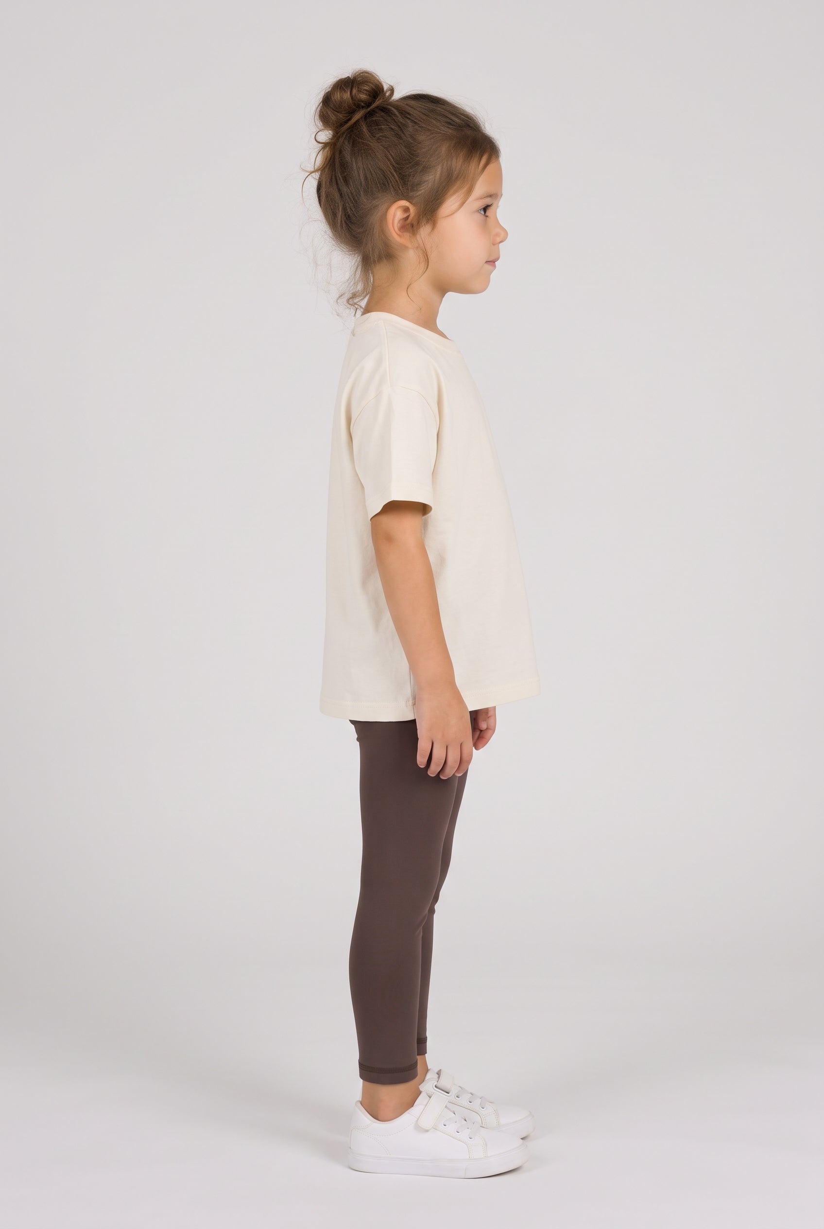 Toddler wearing dark brown full-length leggings with a soft, fitted look, shown from the side.