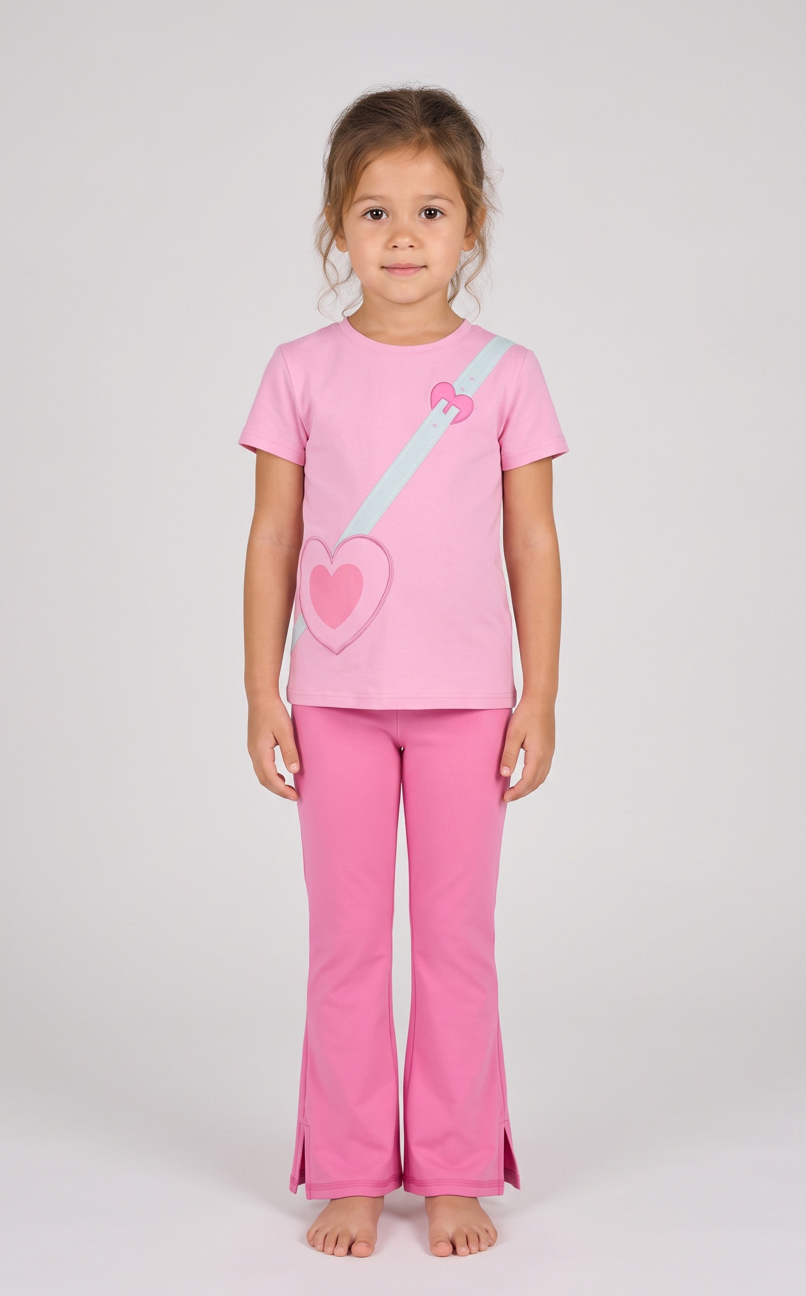 Toddler girl wearing pink short sleeve tee with heart and strap graphic, paired with matching pink flare leggings with front