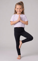 Girl wearing full-length black leggings with a smooth, stretchy finish, posed against a light gray backdrop.