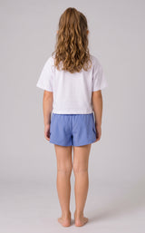 Back view of a girl wearing periwinkle blue running shorts with fluttered outer panels and a white T-shirt.