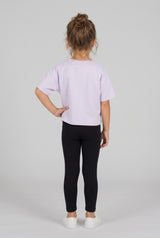 Toddler wearing black fitted leggings with a lavender T-shirt and white sneakers, viewed from behind.