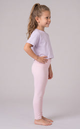 Little girl modeling full-length pale pink leggings with a matching loose T-shirt, shown in side profile.
