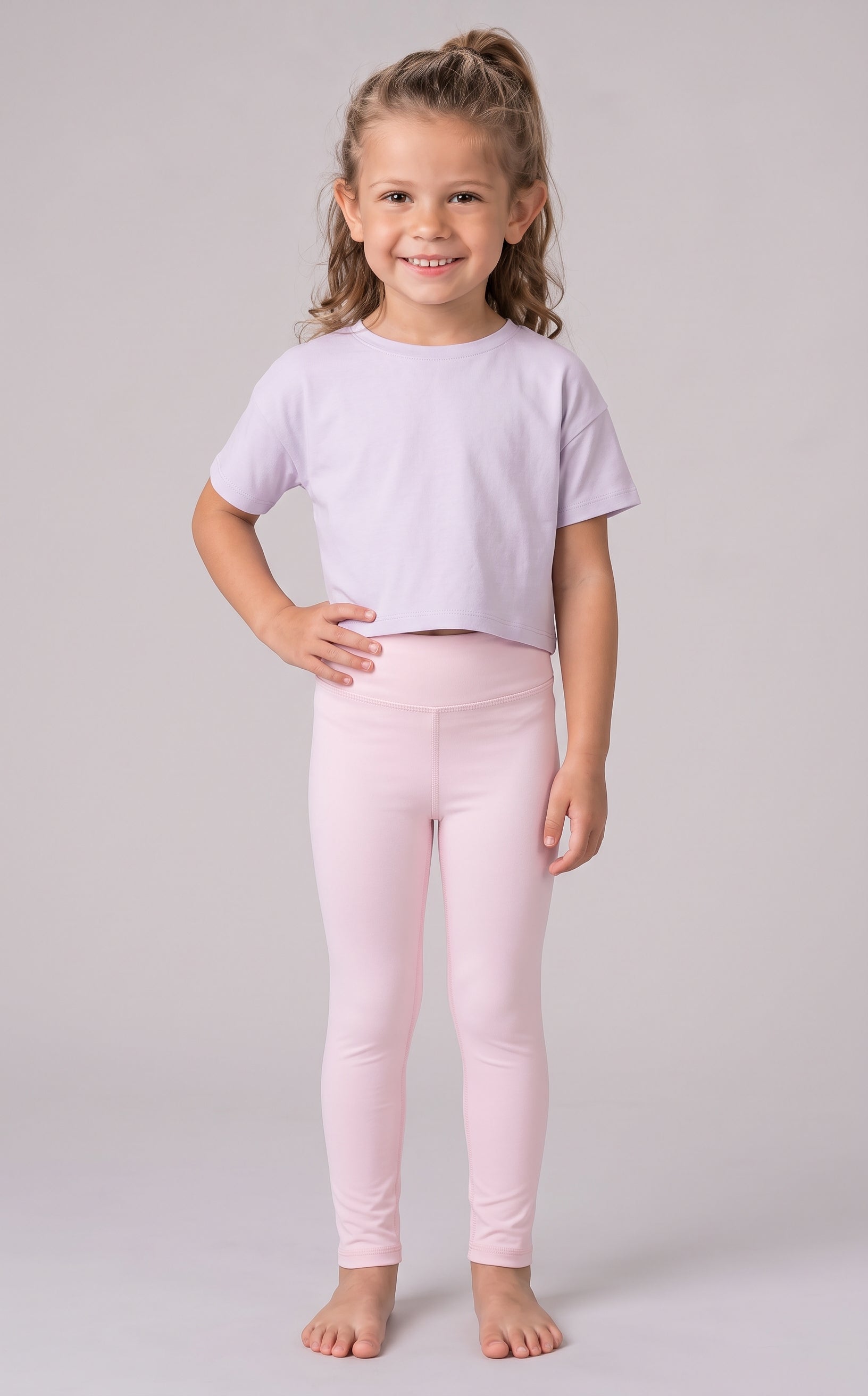Girl modeling a pale pink cropped T-shirt with matching full-length leggings in a smooth stretch fabric.