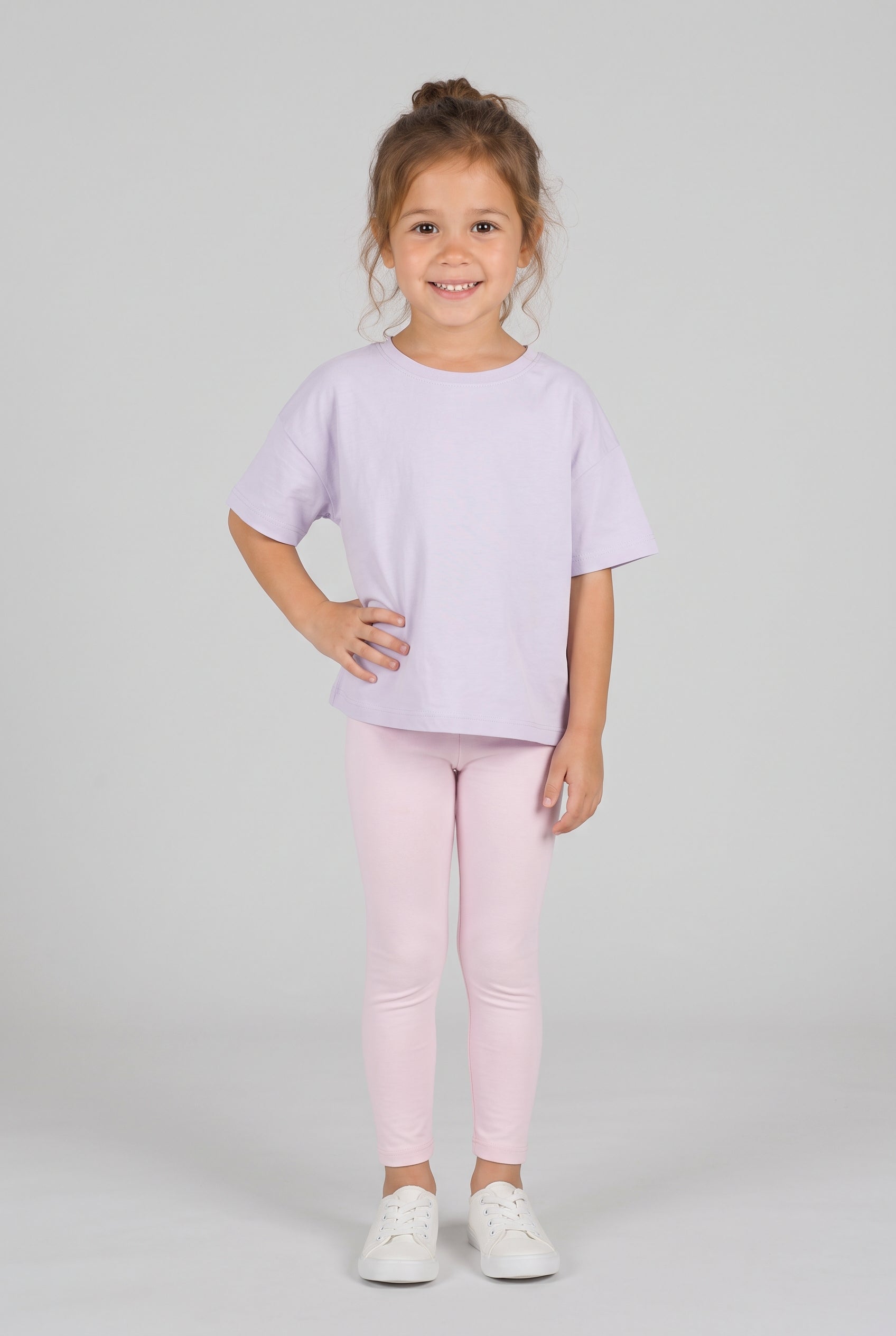 Toddler wearing pale pink leggings with a loose lavender T-shirt and white sneakers.
