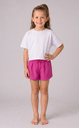 Girl wearing bright pink running shorts with a fluttered outer layer and fitted inner shorts, paired with a white T-shirt.