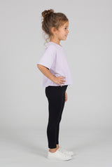 Toddler wearing black full-length leggings with a slim fit, paired with a lavender T-shirt and white sneakers.