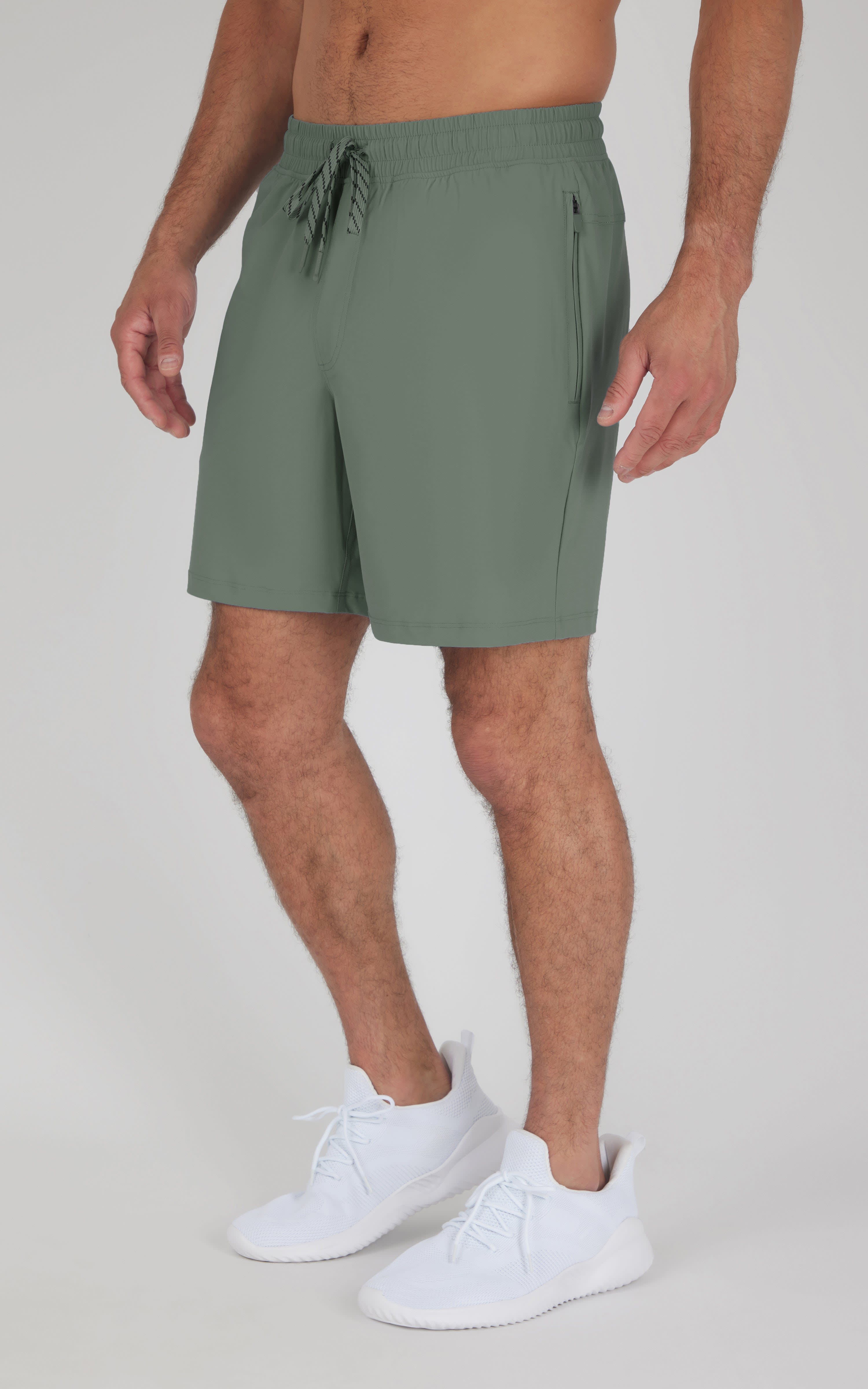 Men's Agave Green 7" shorts with side pockets and drawstring waist, worn with white sneakers.