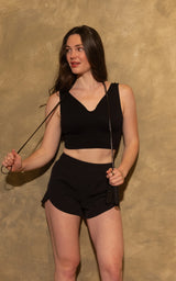 Black lightweight women's running shorts with a curved hem and breathable fabric, modeled with a matching black crop top.