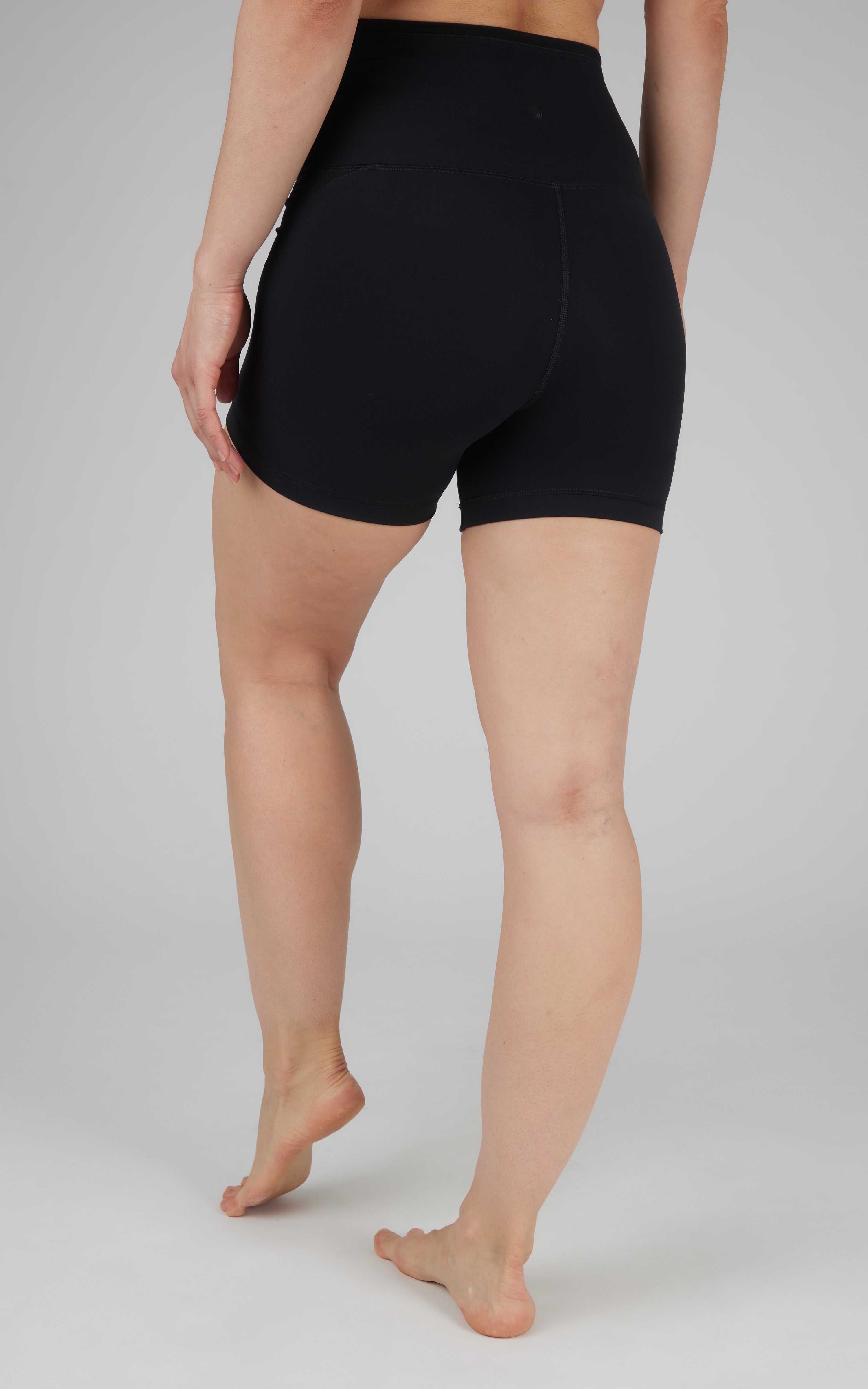 Black high-waist biker shorts with 5-inch inseam on a standing model viewed from the back.