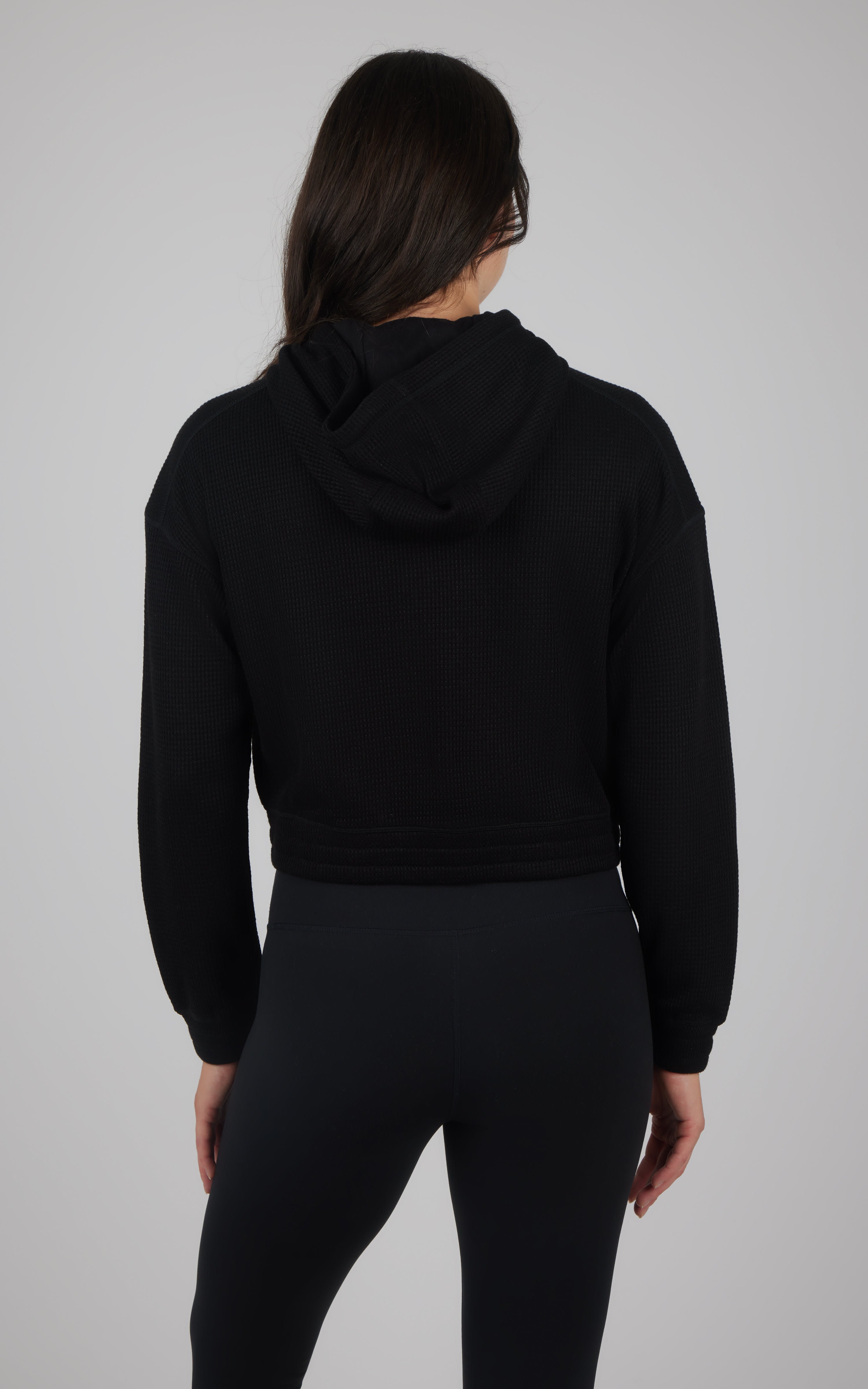 Black cropped hooded jacket with brushed inside, long sleeves, and fitted waistband, shown from back.