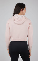 Light pink cropped hooded jacket with brushed interior and long sleeves, worn with black leggings.
