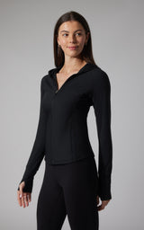 Black ribbed full zip hoodie jacket with thumbholes and fitted silhouette on a woman.