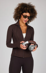 Dark brown full-zip runner jacket with high collar and fitted silhouette worn with matching leggings.