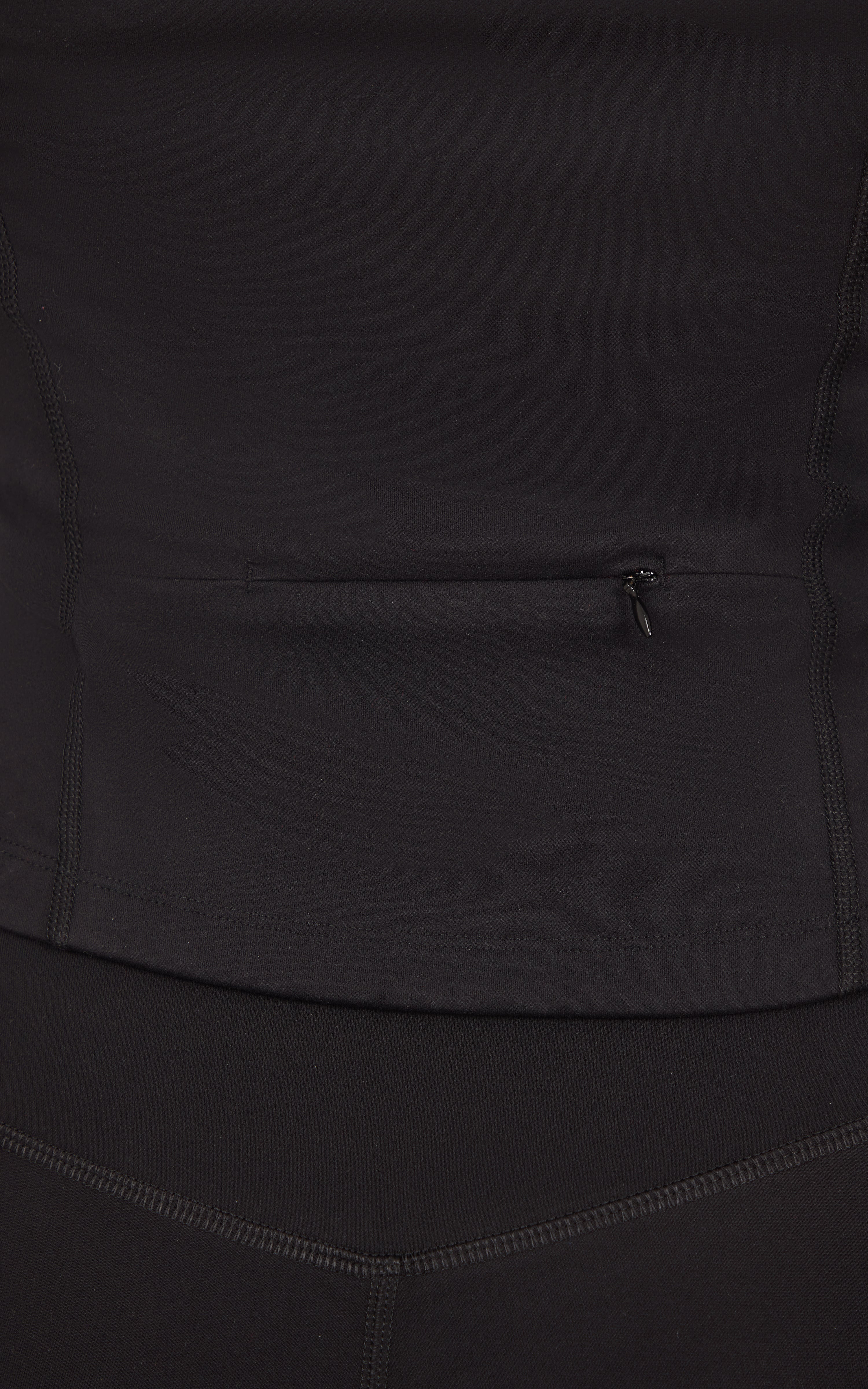 Close-up of a dark charcoal jacket with a small horizontal zip pocket and curved seam detailing.