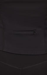 Close-up of a dark charcoal jacket with a small horizontal zip pocket and curved seam detailing.