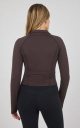 Back view of a fitted dark brown raglan jacket with long sleeves and a high collar, paired with black leggings.
