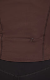Close-up of a dark brown jacket with a horizontal zippered chest pocket and curved seam detailing.