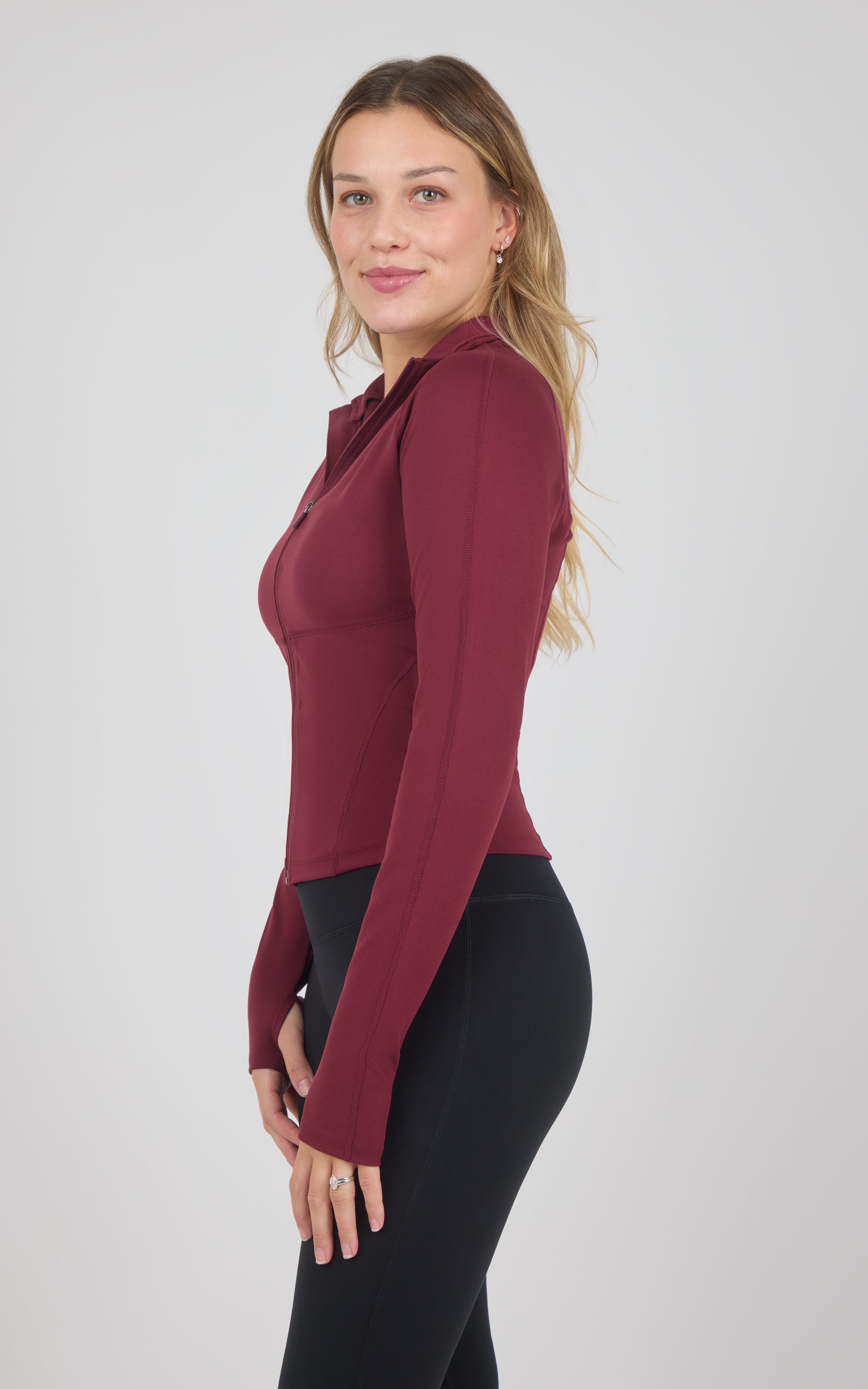 Burgundy full-zip raglan jacket with a fitted silhouette, long sleeves, and a high collar, shown from the side.