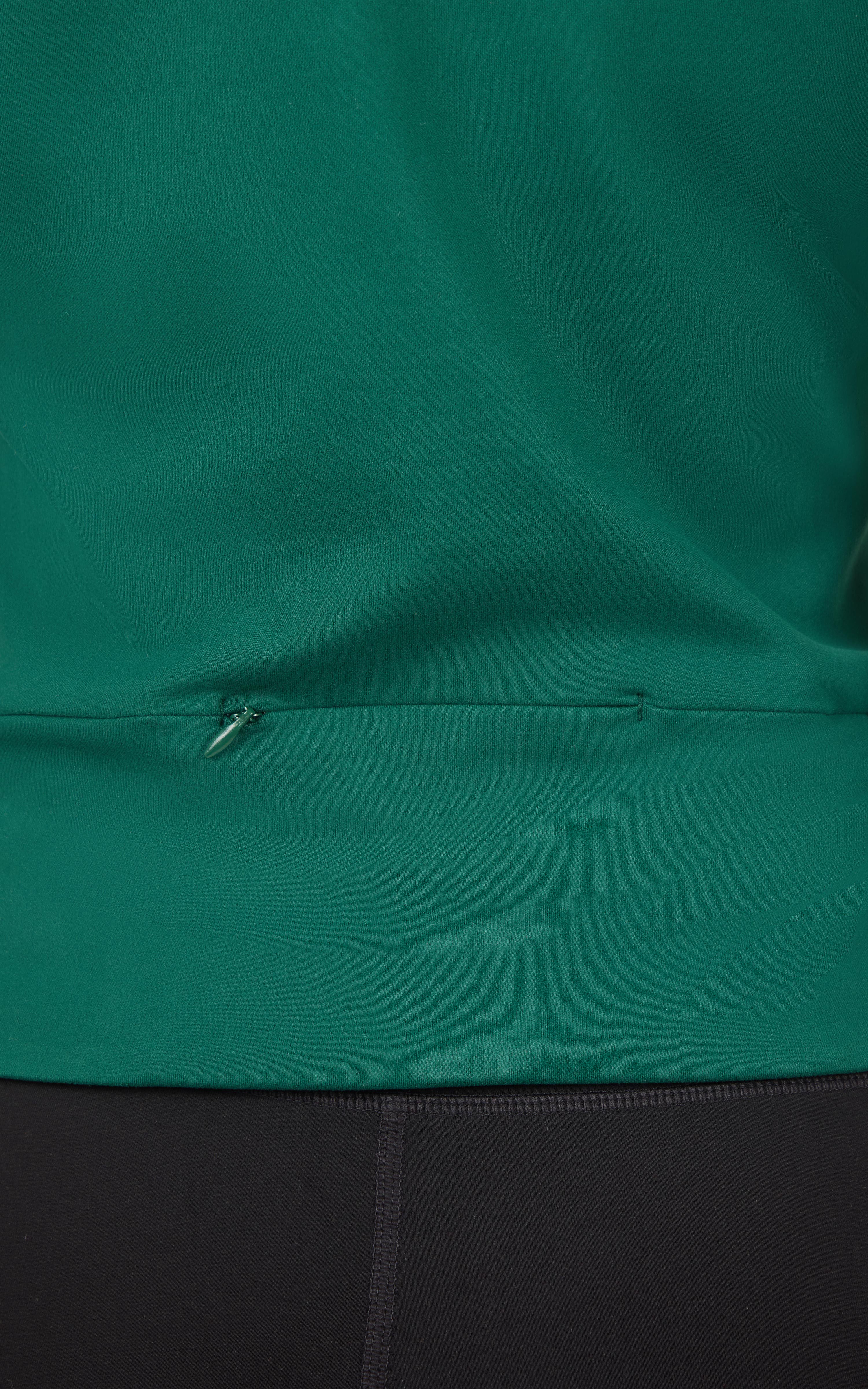 Close-up of dark green full zip jacket hem with adjustable drawstring and smooth fabric texture.