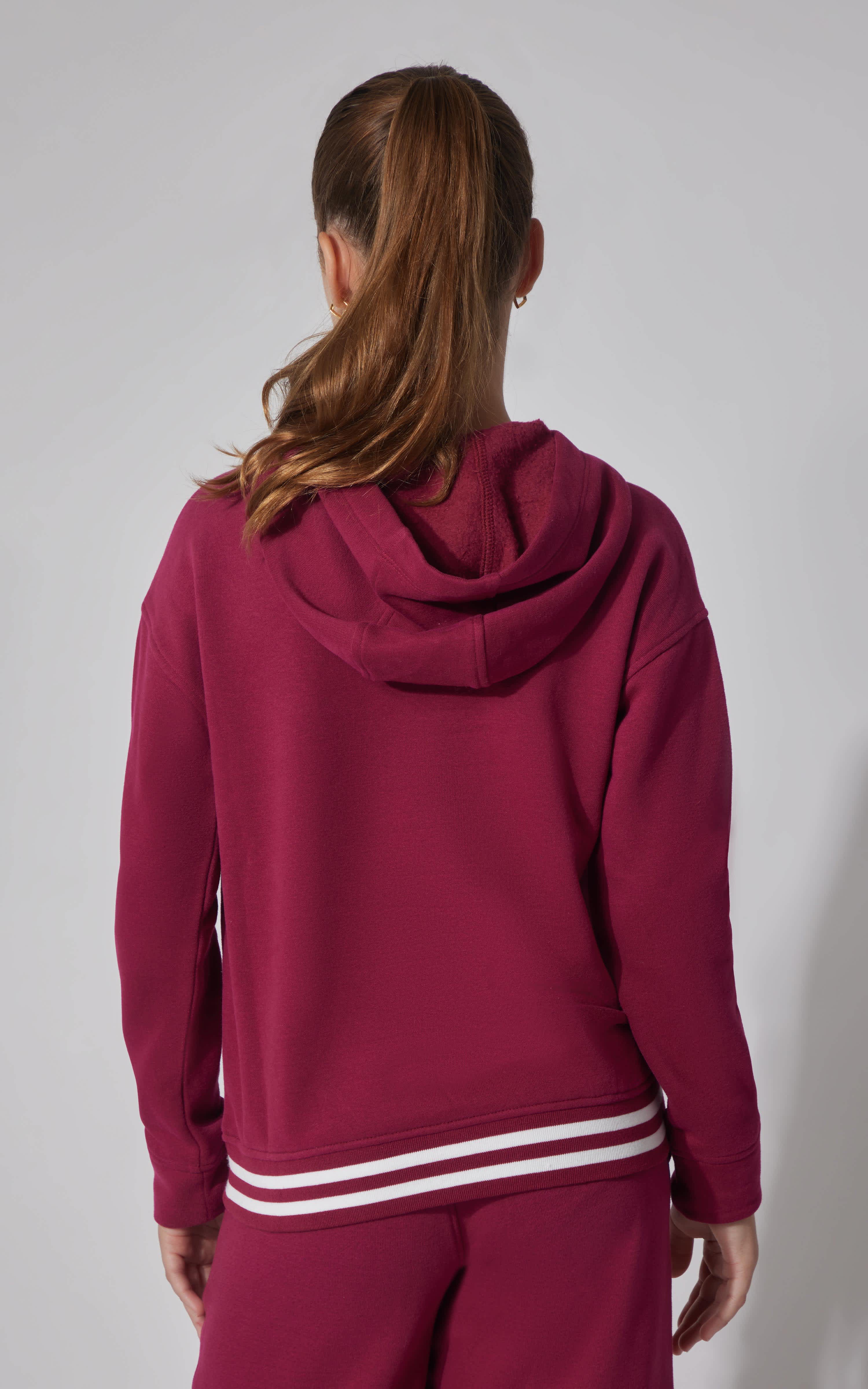 Berry Blast fleece pullover hoodie with hood and striped ribbed hem on a girl seen from back.