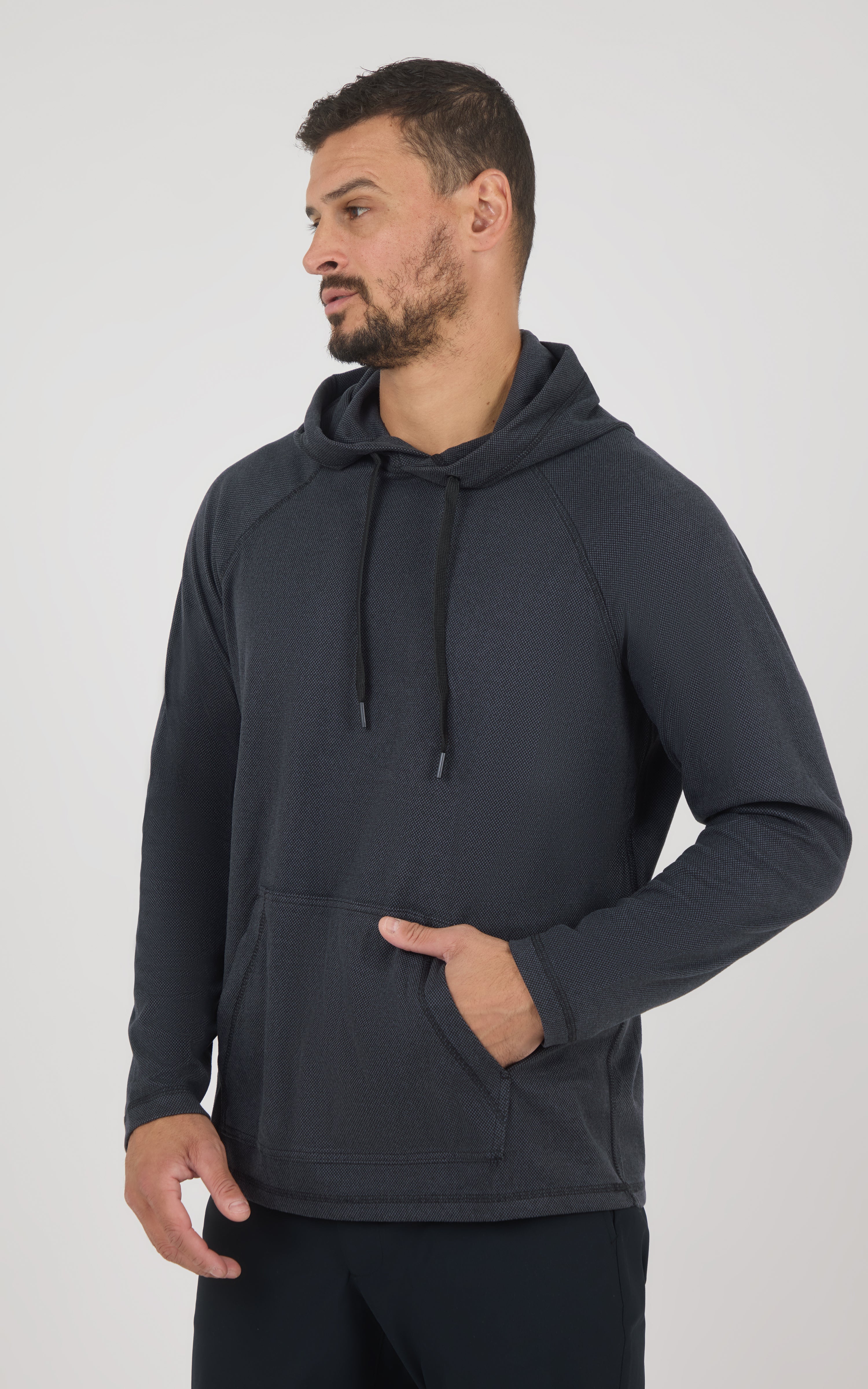 Men’s dark gray soft fabric hoodie with adjustable drawstring hood and kangaroo pocket, worn by model facing left.