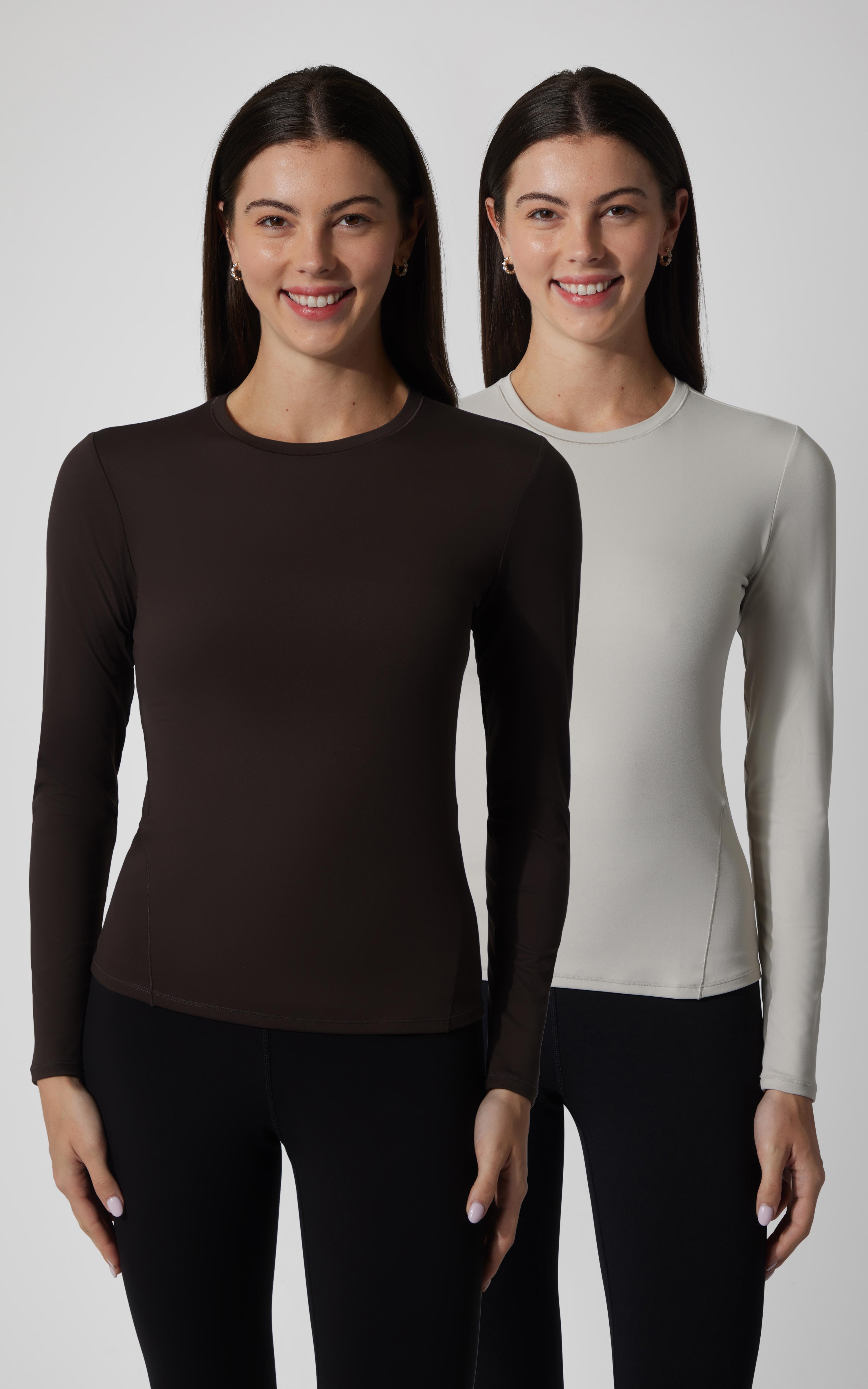 Two women wearing fitted long sleeve tops in dark brown and light gray, paired with black pants.