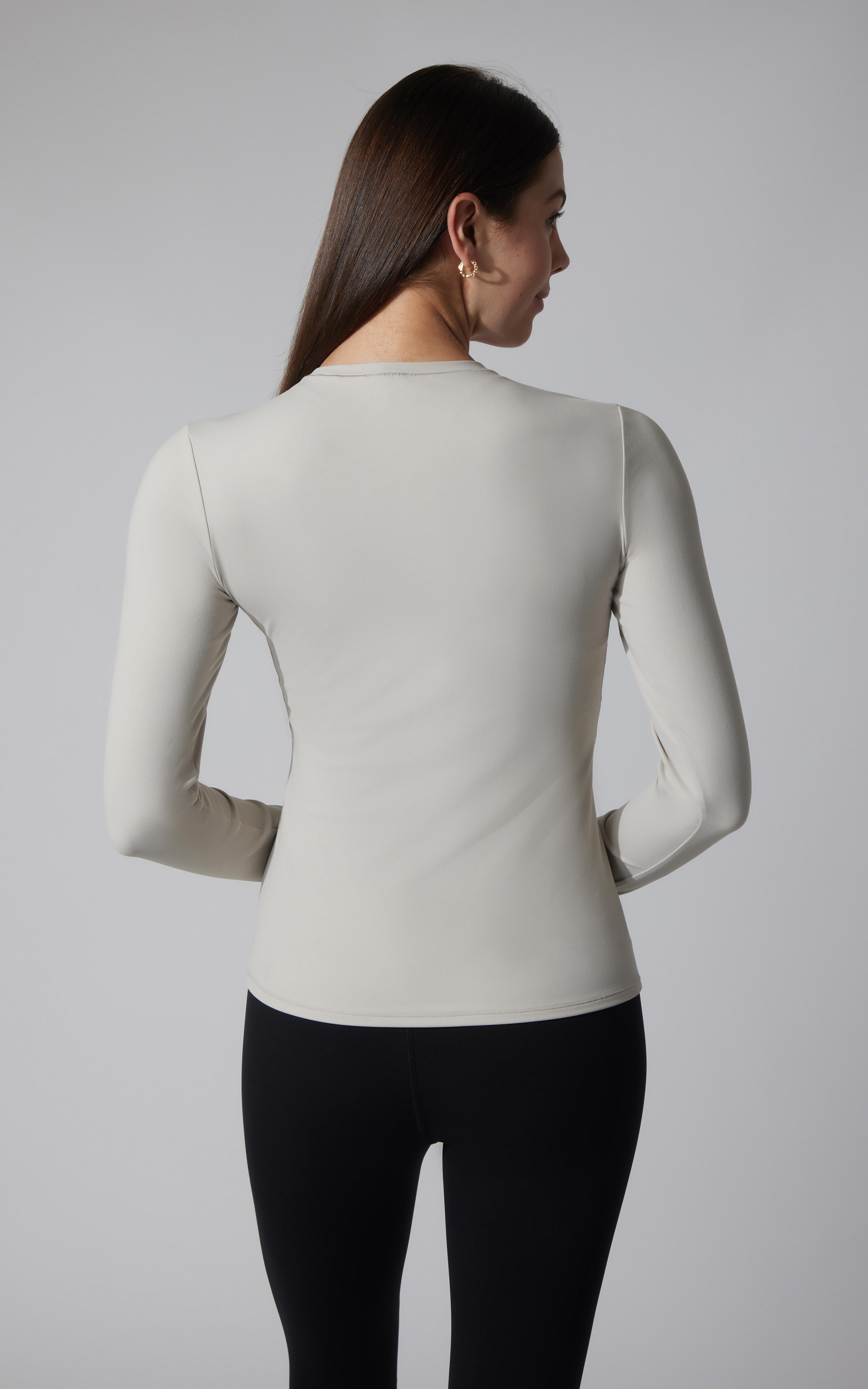 Women's fitted long sleeve top in light gray with crew neckline and smooth fabric.