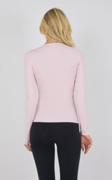 Chalk pink long sleeve fitted top with crew neck on woman facing away.